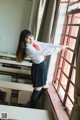 A woman in a school uniform leaning against a window.