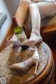 A woman sitting on a table with a glass of wine and a pair of shoes.