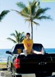 A woman sitting in the back of a truck on the beach.