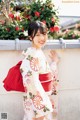 A woman in a kimono leaning against a wall.