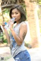 A woman in jeans and a tank top drinking water from a bottle.