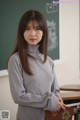 A woman standing in front of a blackboard holding a book.