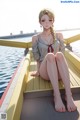 A woman sitting on a wooden dock next to a body of water.