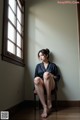 A woman sitting on a chair in front of a window.