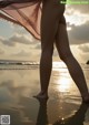 A woman standing on a beach with her back to the camera.