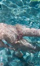 A person swimming in the clear blue water of a pool.