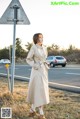 A woman standing next to a street sign on the side of the road.