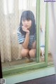 A young woman sitting in front of a green window.