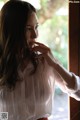 A woman in a white blouse and red polka dot skirt looking out a window.