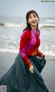 A woman in a colorful shirt and skirt on the beach.