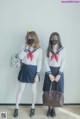 Two young women in school uniforms standing next to each other.