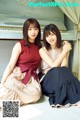 Two young women sitting next to each other in front of a piano.