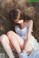 A woman in a white dress sitting in a field.