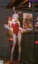 A woman in a red bodysuit and bunny ears posing for a picture.