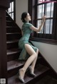 A woman in a green dress sitting on a set of stairs.