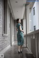 A woman in a green dress standing on a balcony.