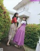 Two young women standing next to each other in front of a house.