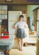 A woman standing in a kitchen next to a refrigerator.