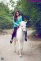 A woman riding on the back of a white horse.