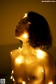 A naked woman with a string of lights around her neck.